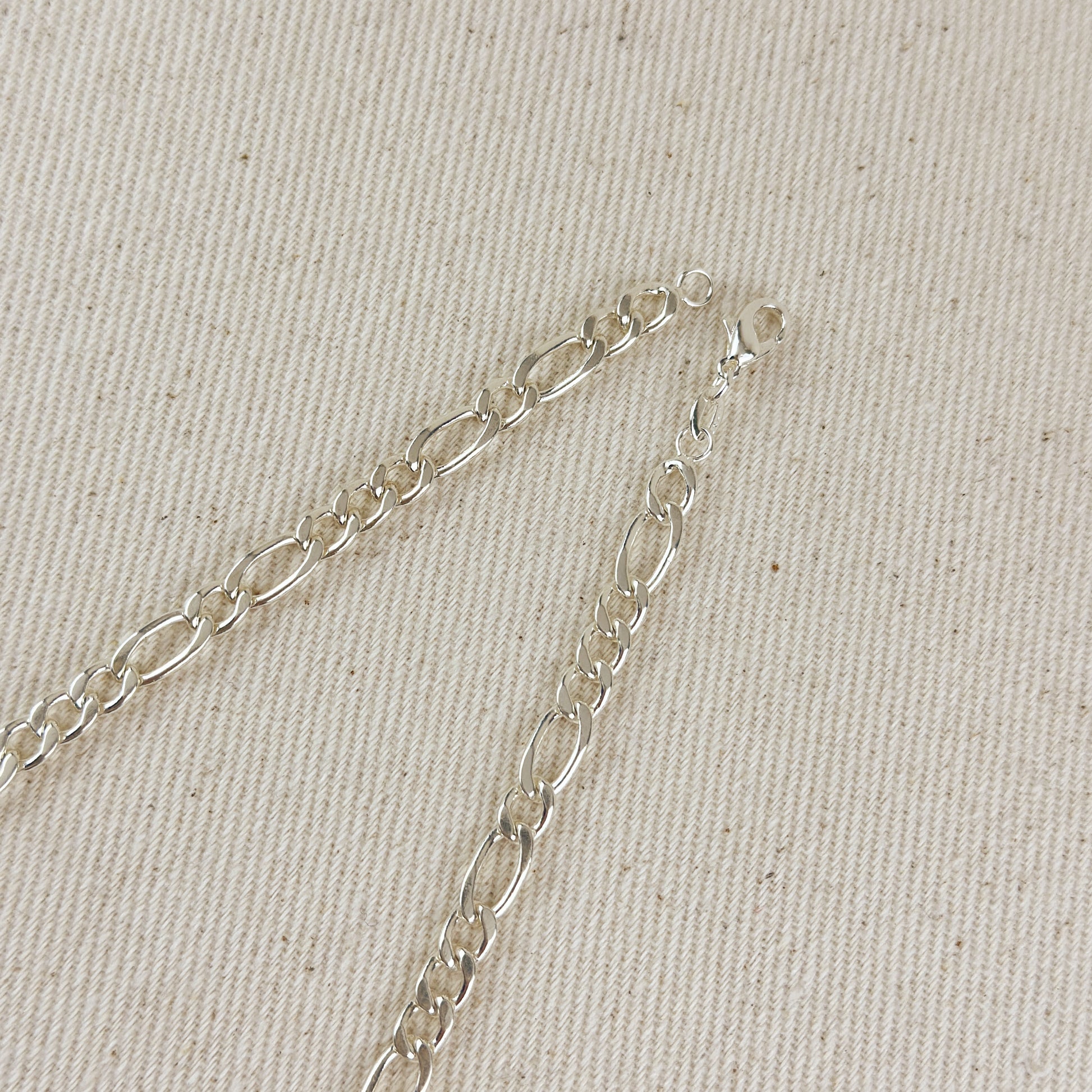 Silver chain bracelet on a beige fabric background