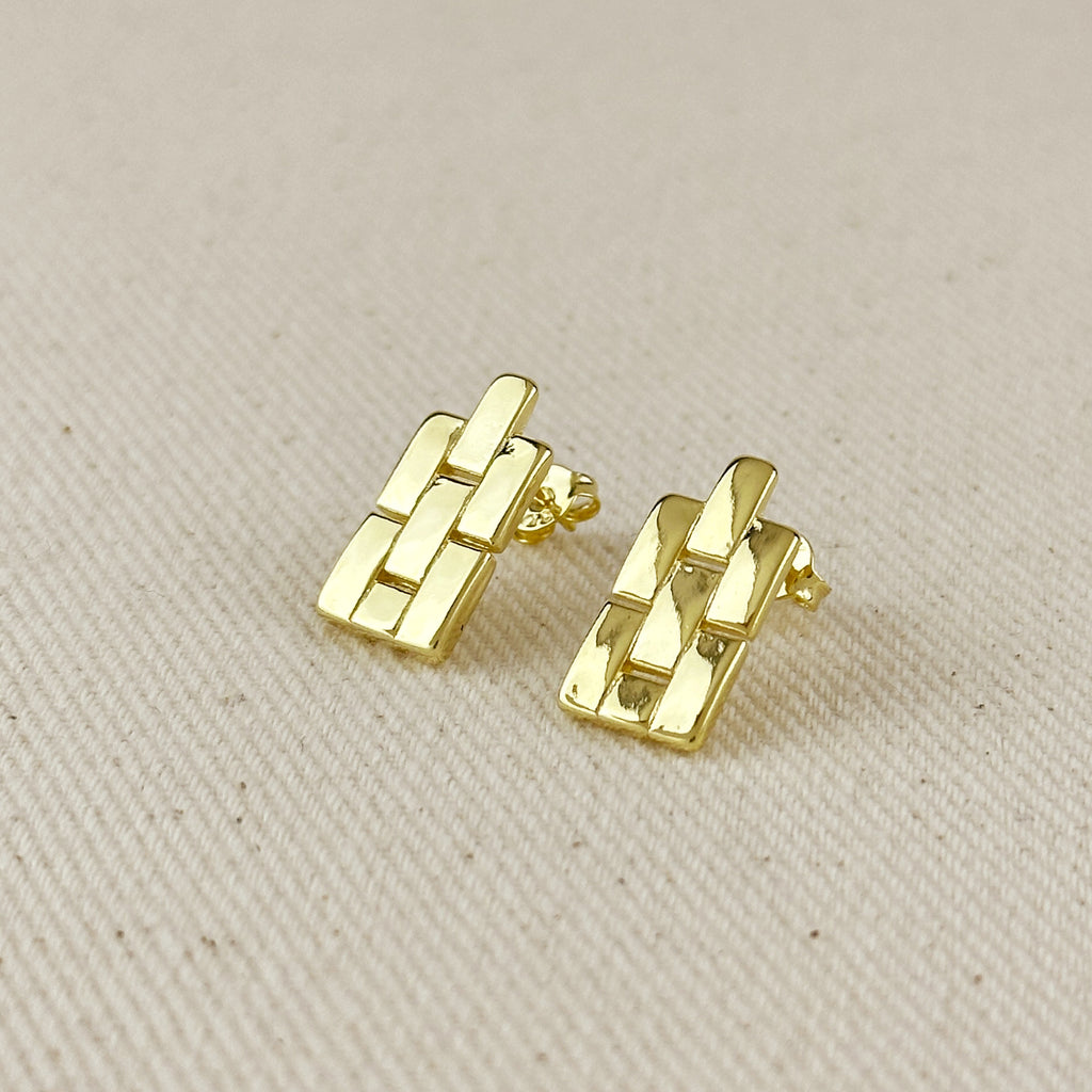 Gold earrings on a beige fabric background