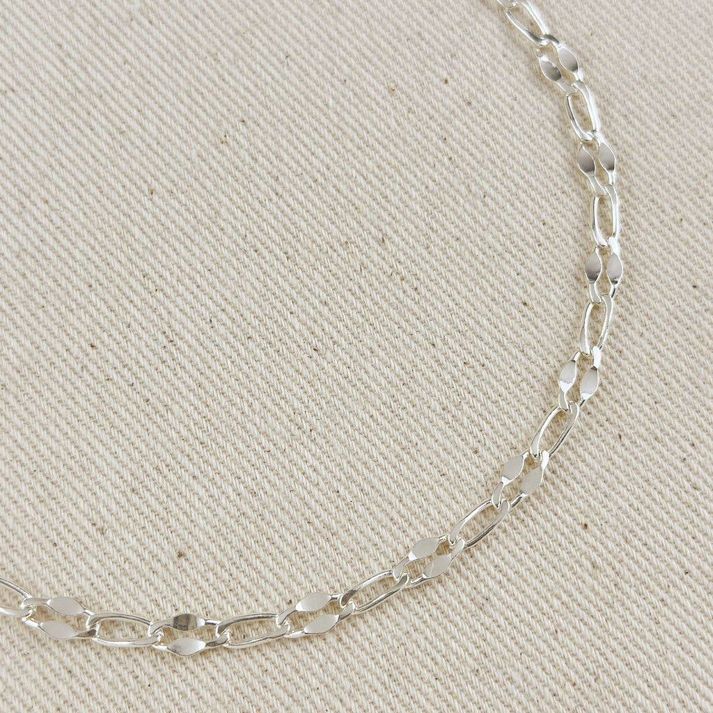 Silver chain necklace on a beige fabric background