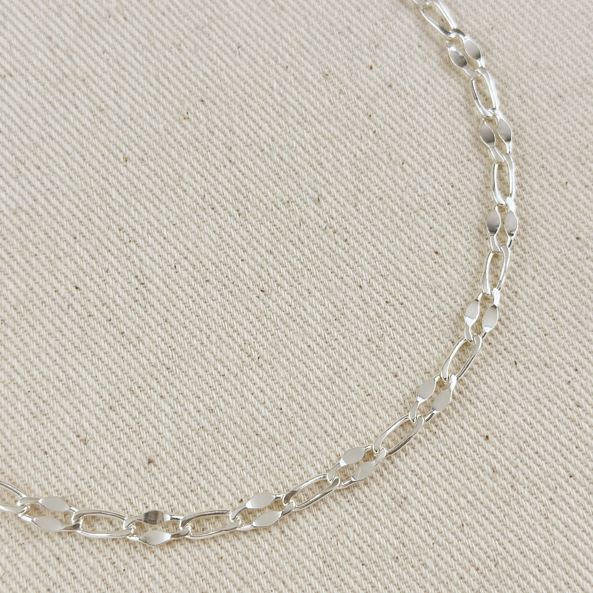 Silver chain necklace on a beige fabric background