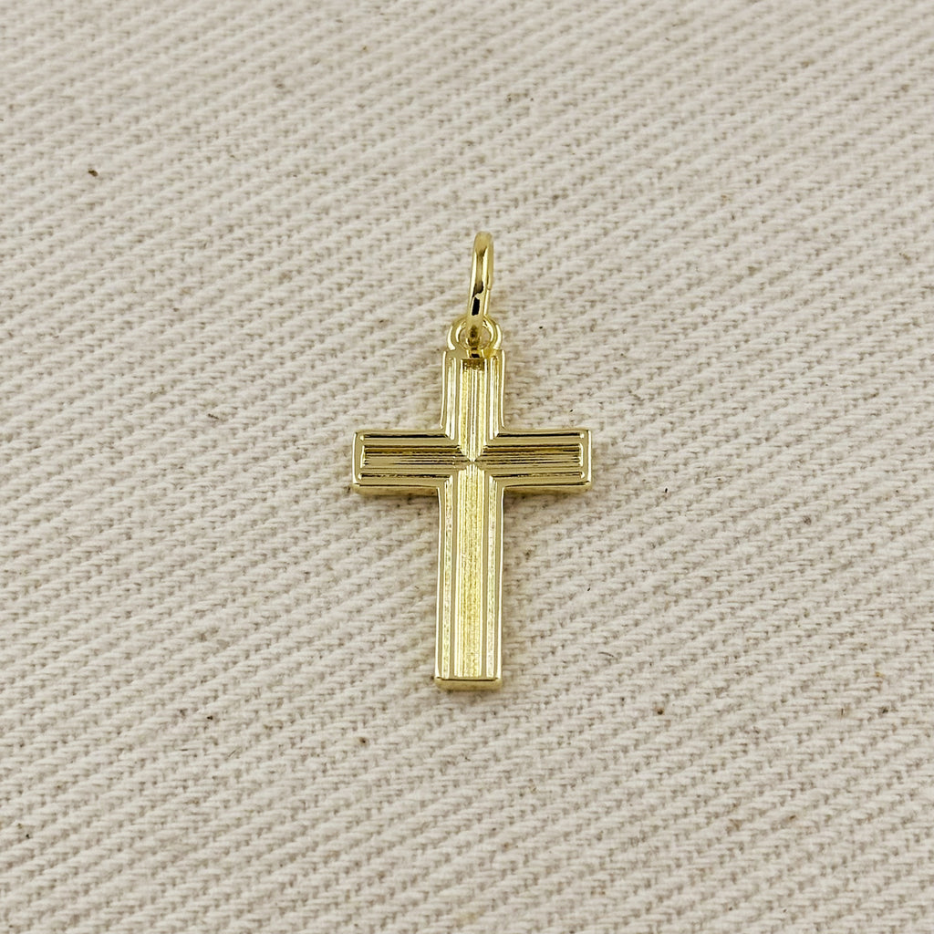 Gold cross pendant on a beige fabric background