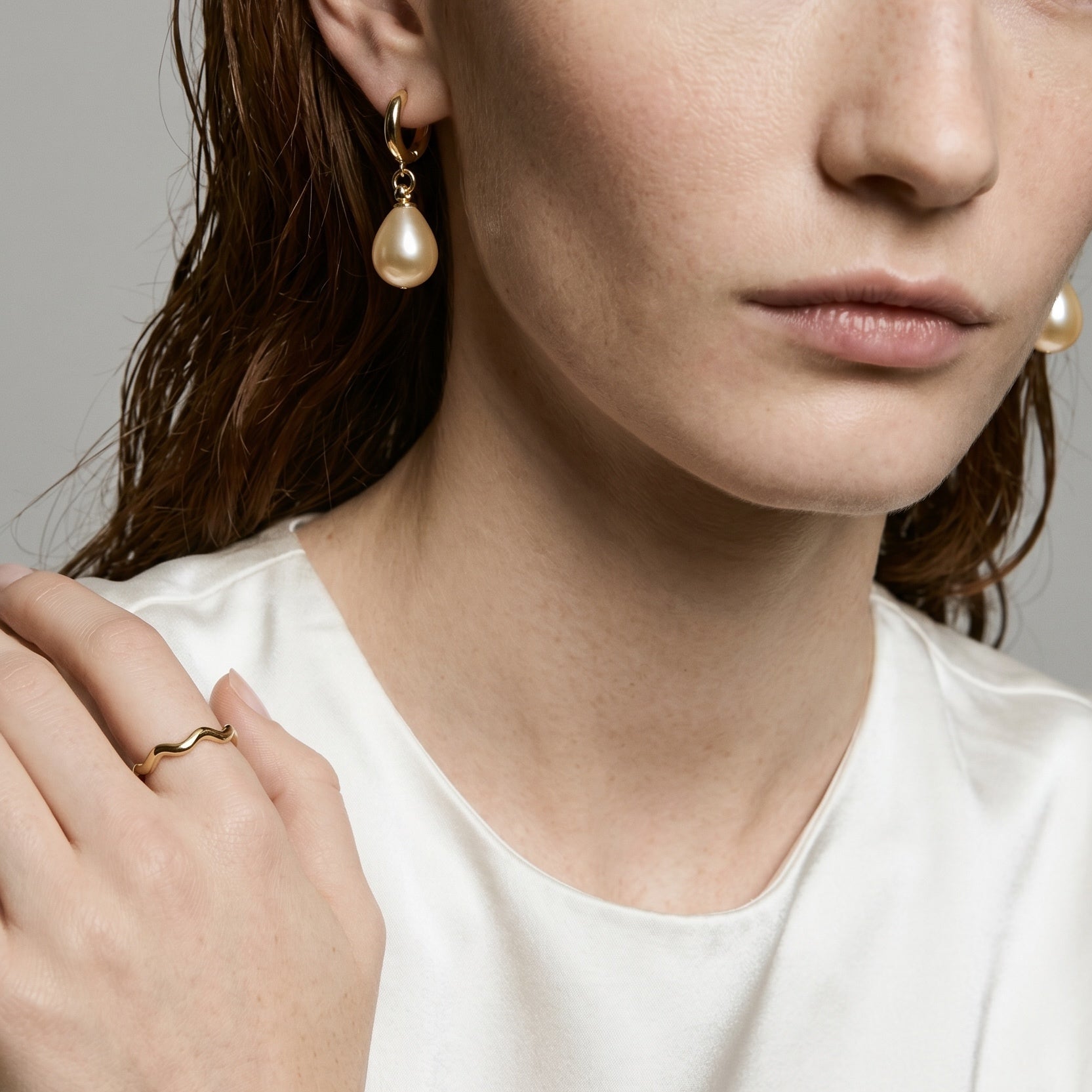 Woman wearing pearl earrings against a neutral background