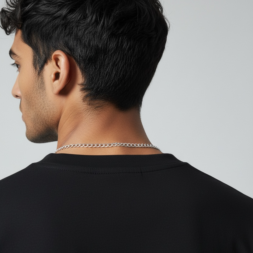 Man wearing a black shirt with a silver chain necklace on a gray background
