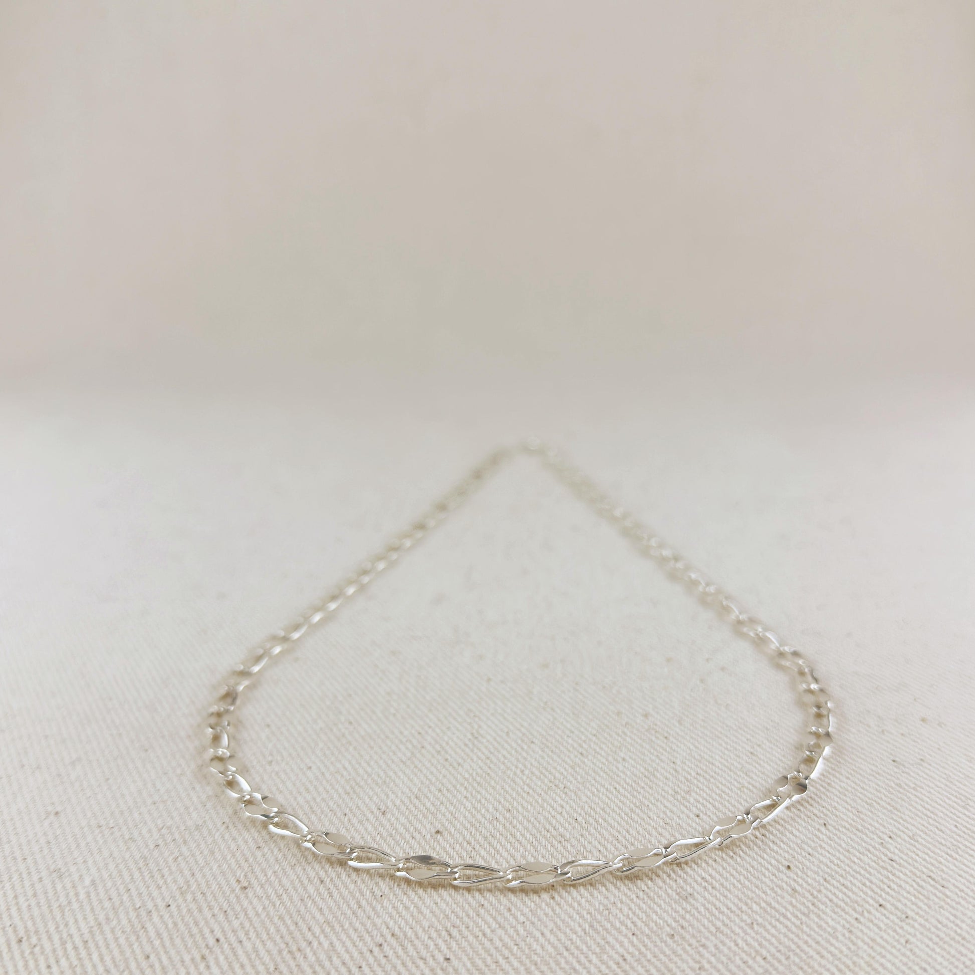 Silver bracelet on a light beige fabric background