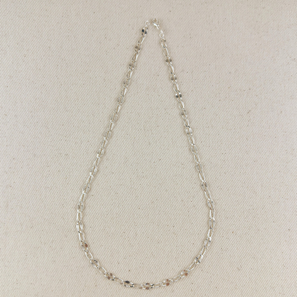Silver chain necklace on a light beige fabric background