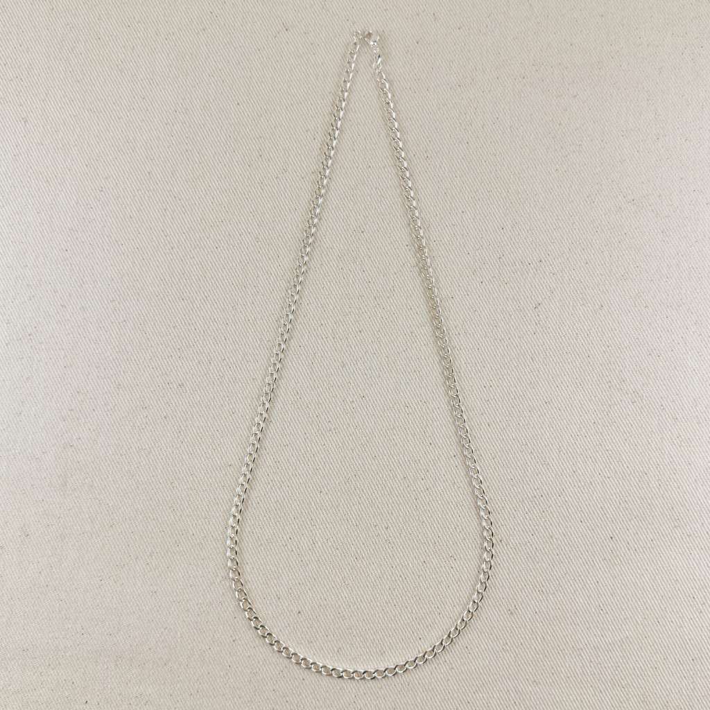 Silver chain necklace on a light beige fabric background