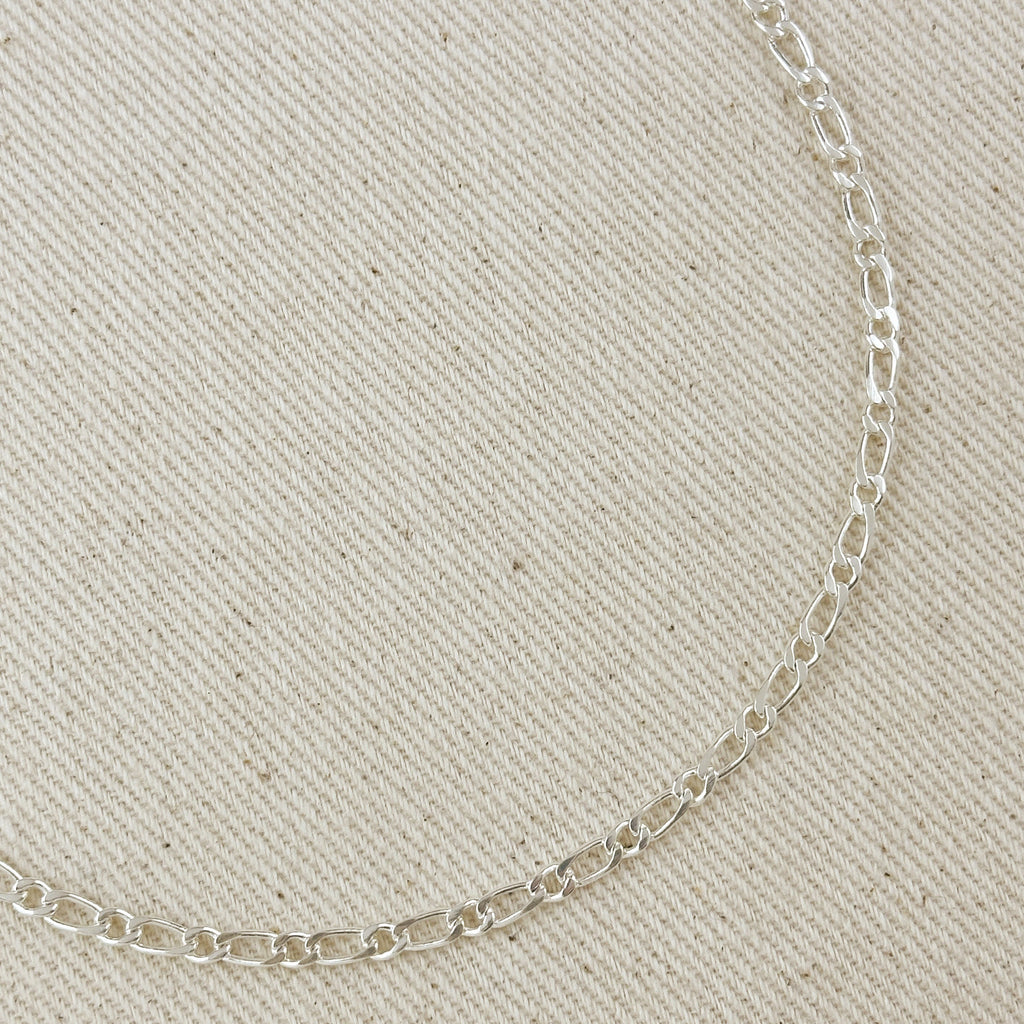 Silver chain necklace on a beige fabric background