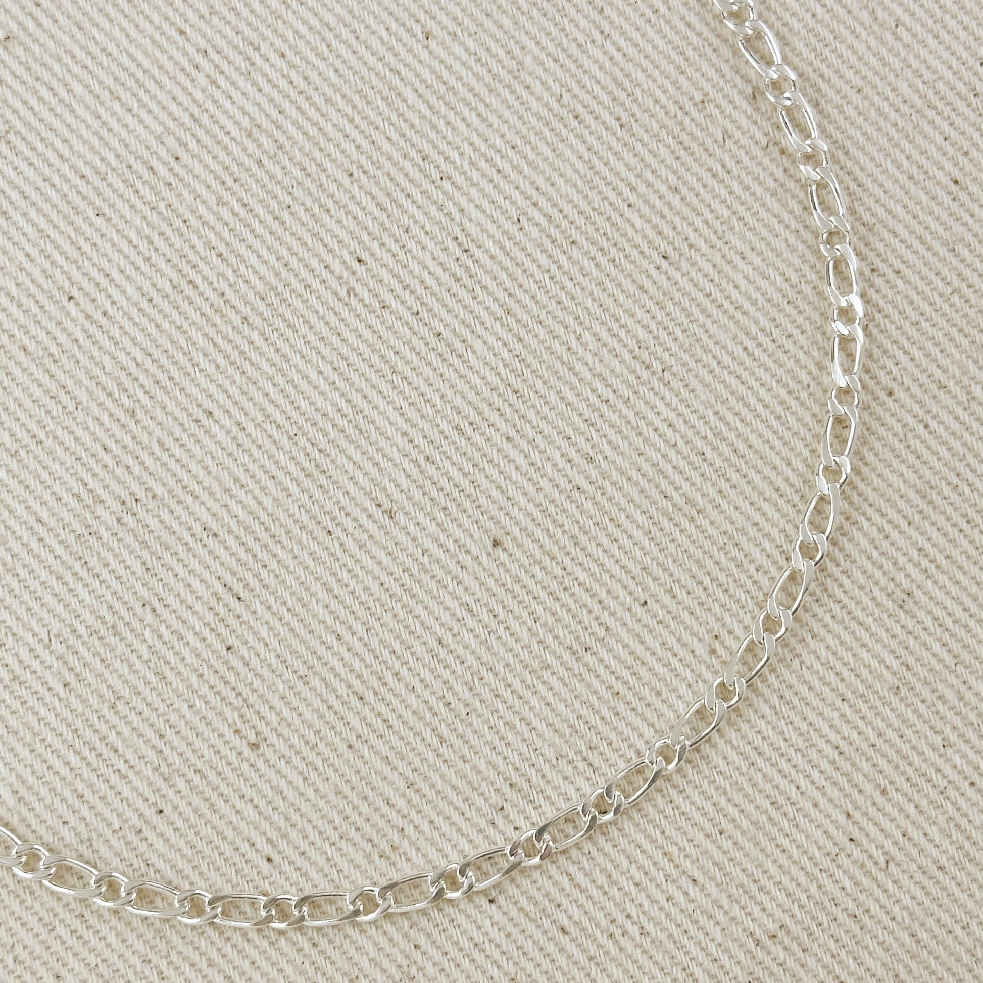 Silver chain necklace on a beige fabric background