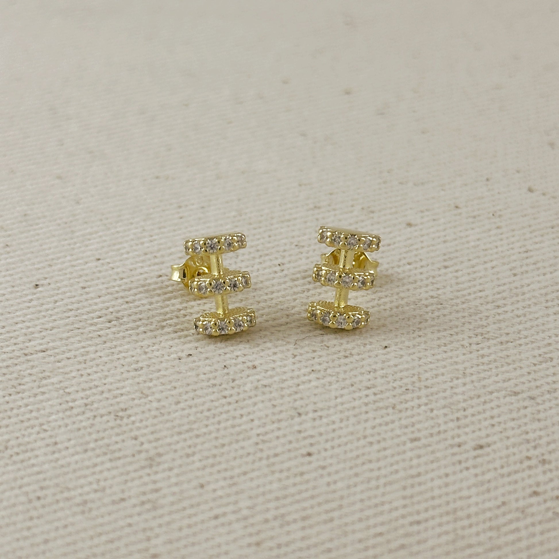 Gold earrings with small diamonds on a beige fabric background