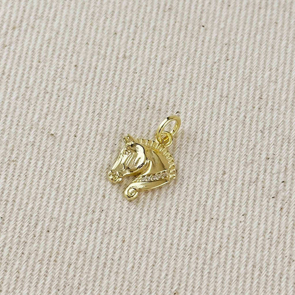 Gold fish-shaped pendant on a textured beige fabric background