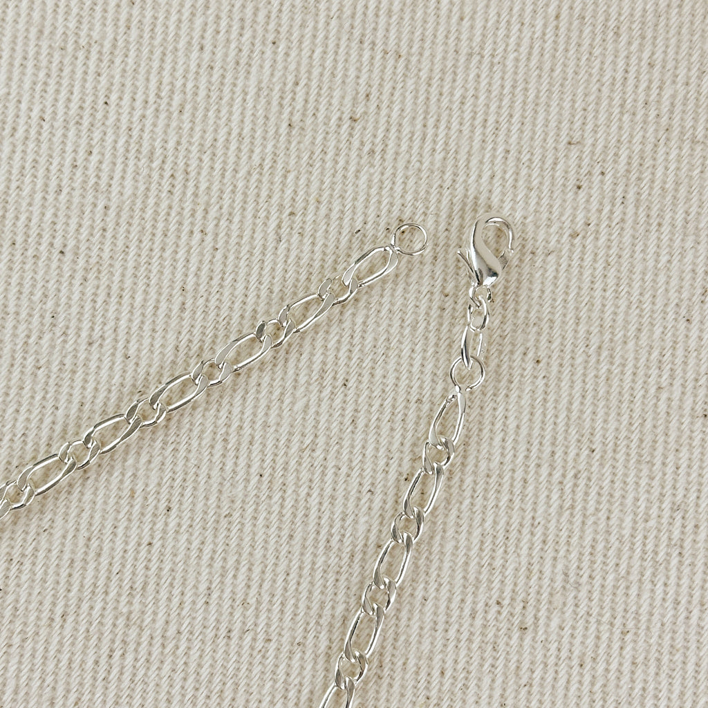 Silver chain necklace on a beige fabric background