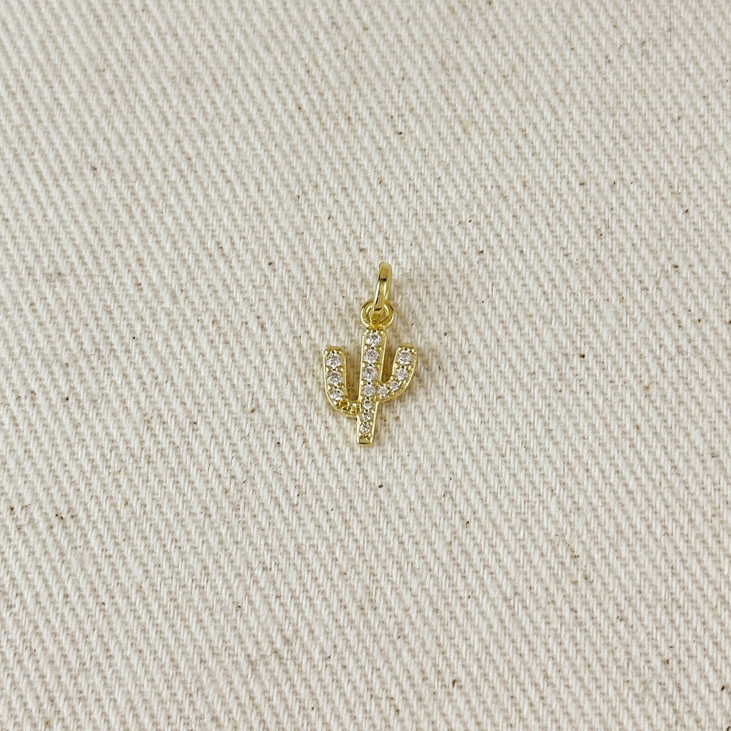 Gold cactus-shaped pendant on a beige fabric background