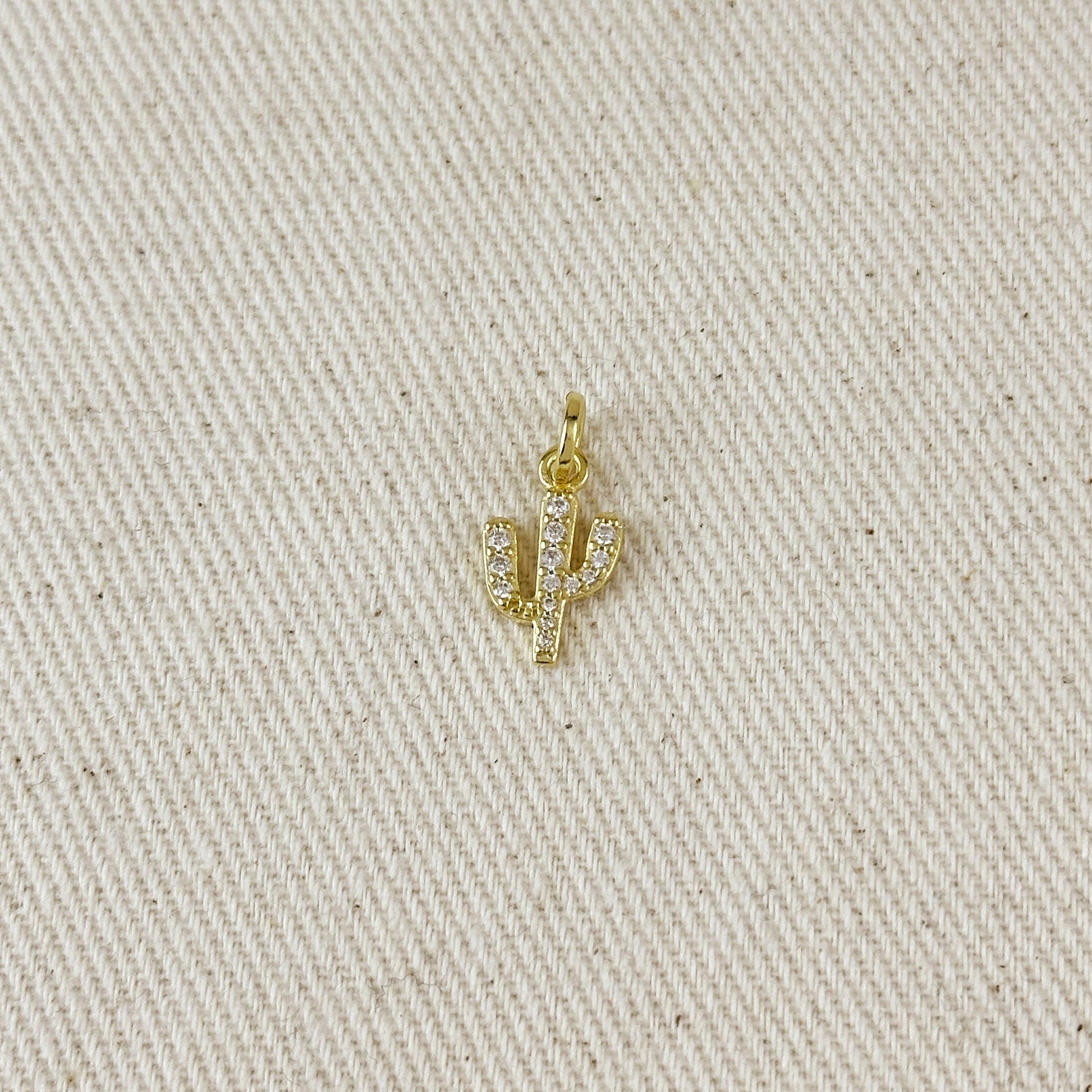 Gold cactus-shaped pendant on a beige fabric background
