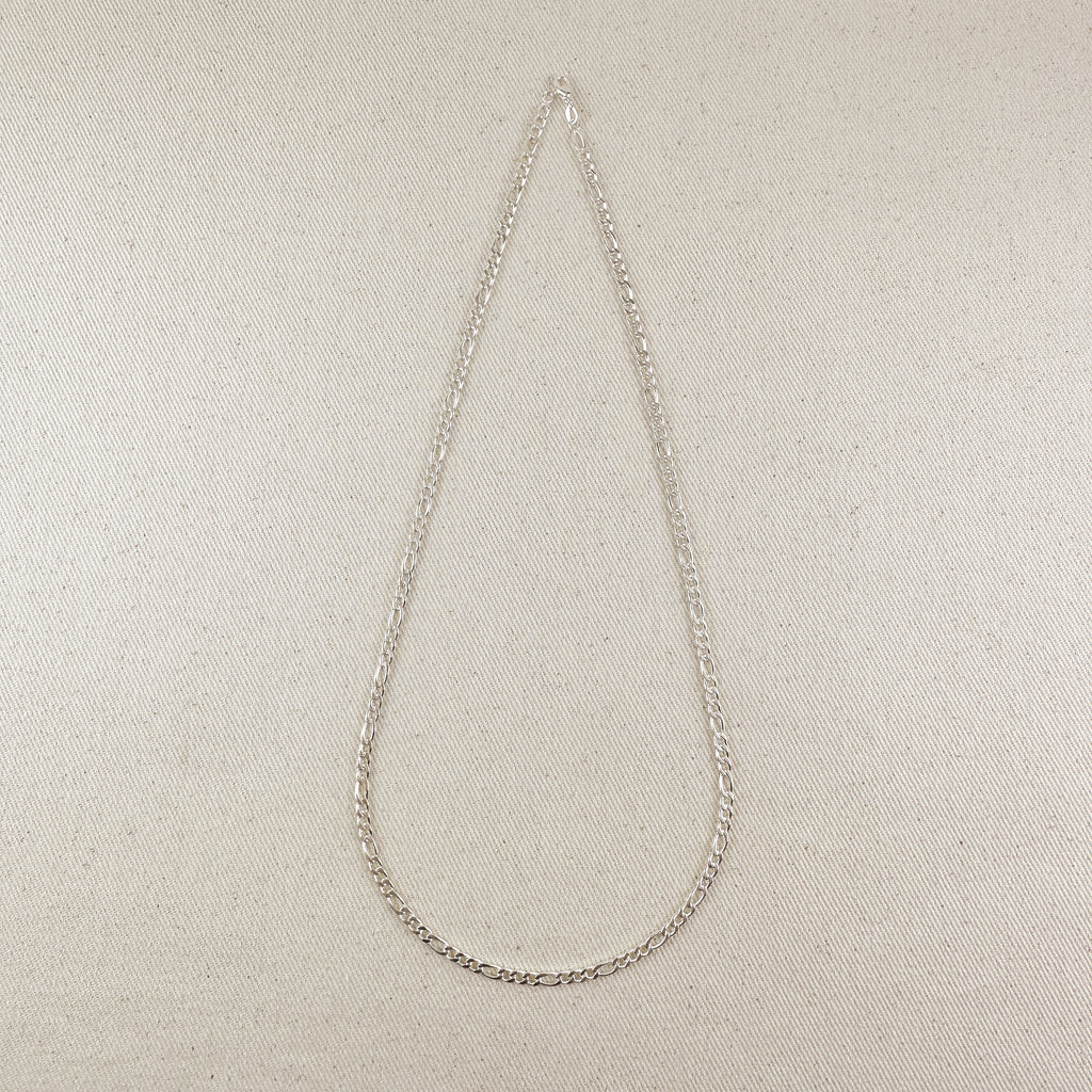 Silver chain necklace on a beige fabric background