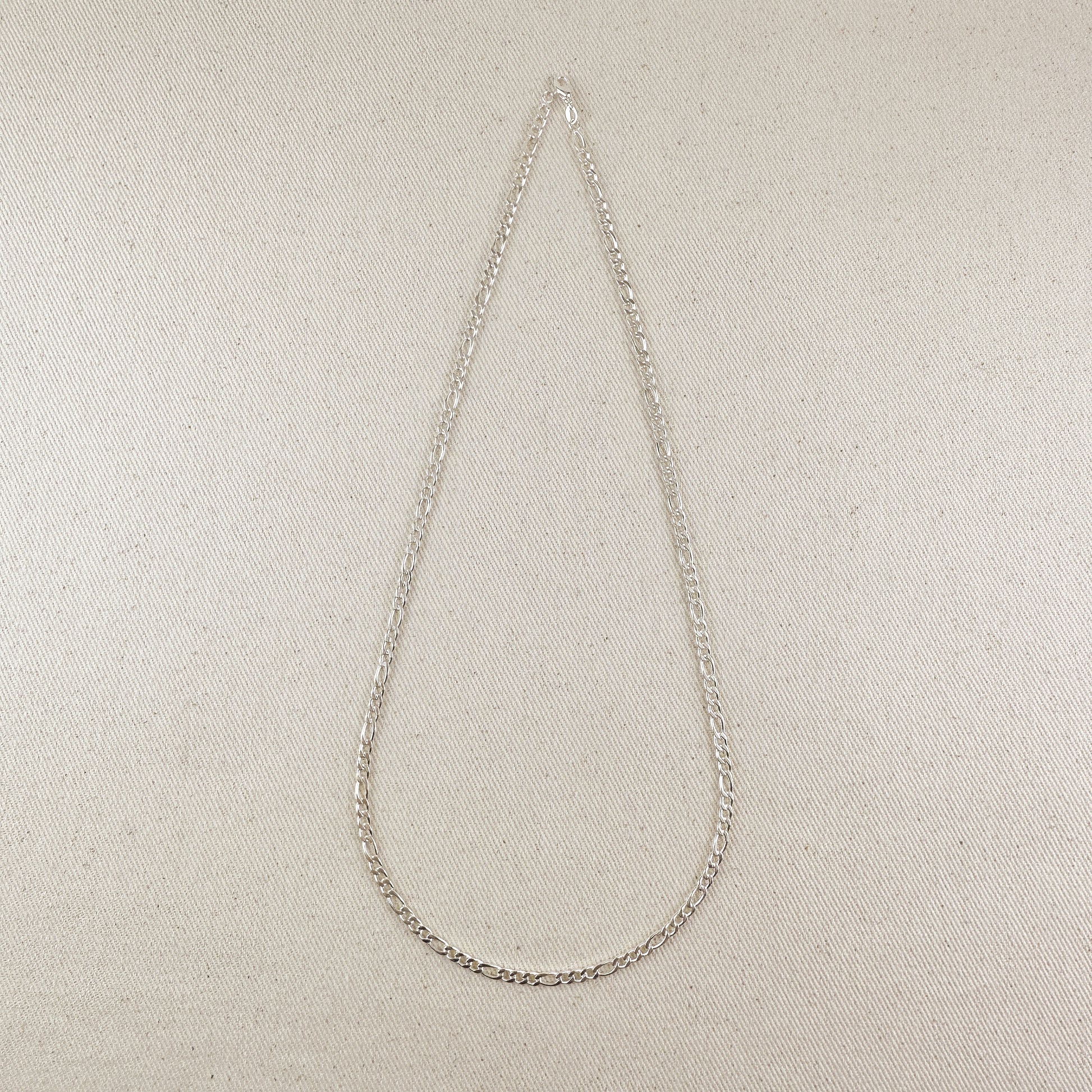 Silver chain necklace on a beige fabric background