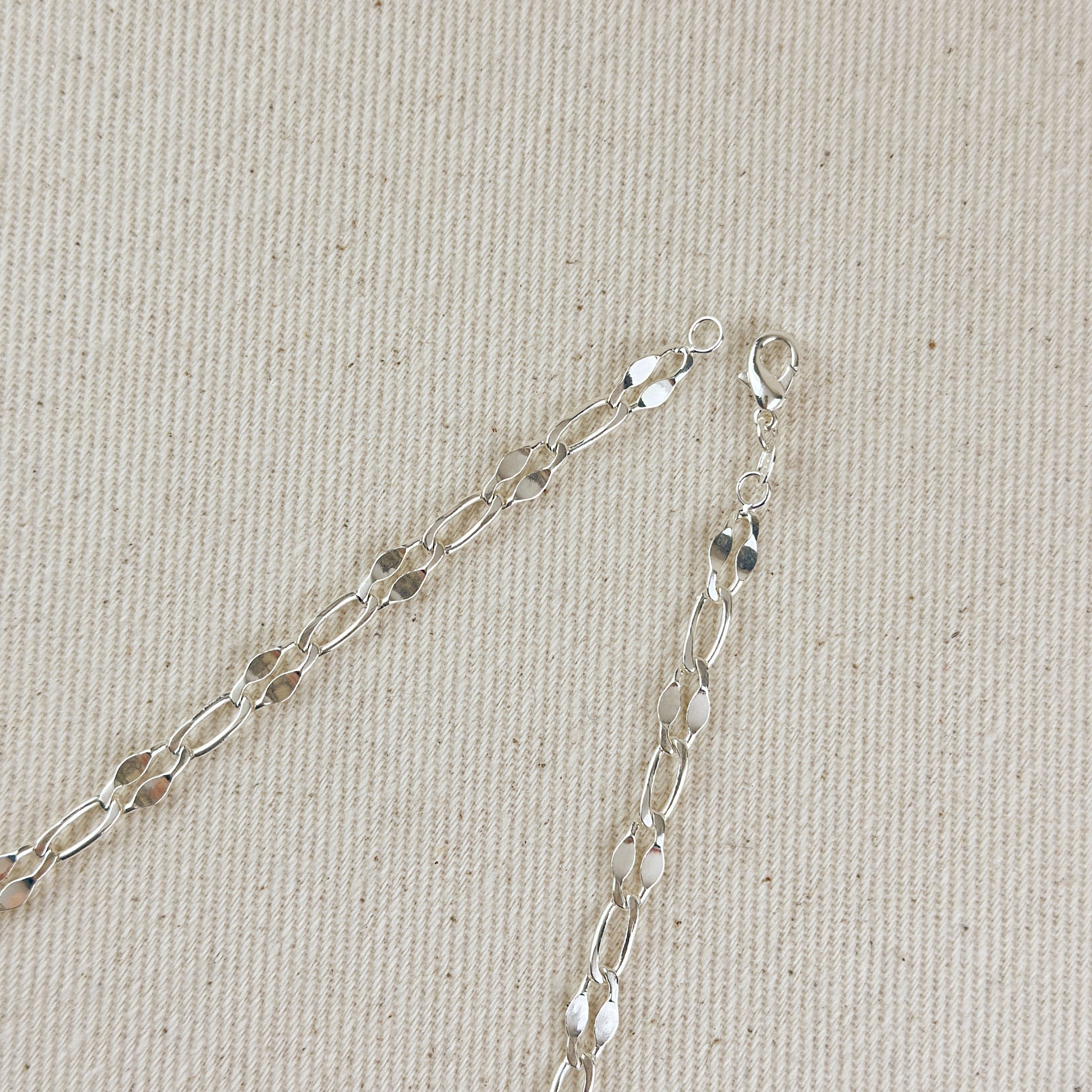 Silver chain necklace on a beige fabric background