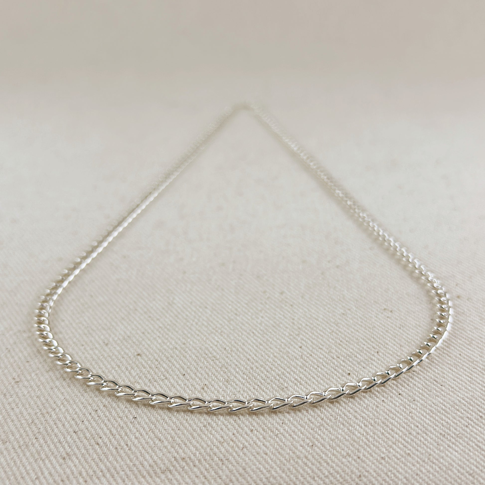 Silver chain necklace on a light beige fabric background