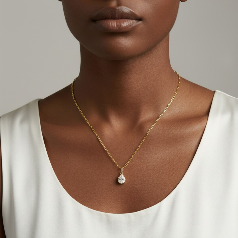 Woman wearing a gold necklace with a pendant against a neutral background