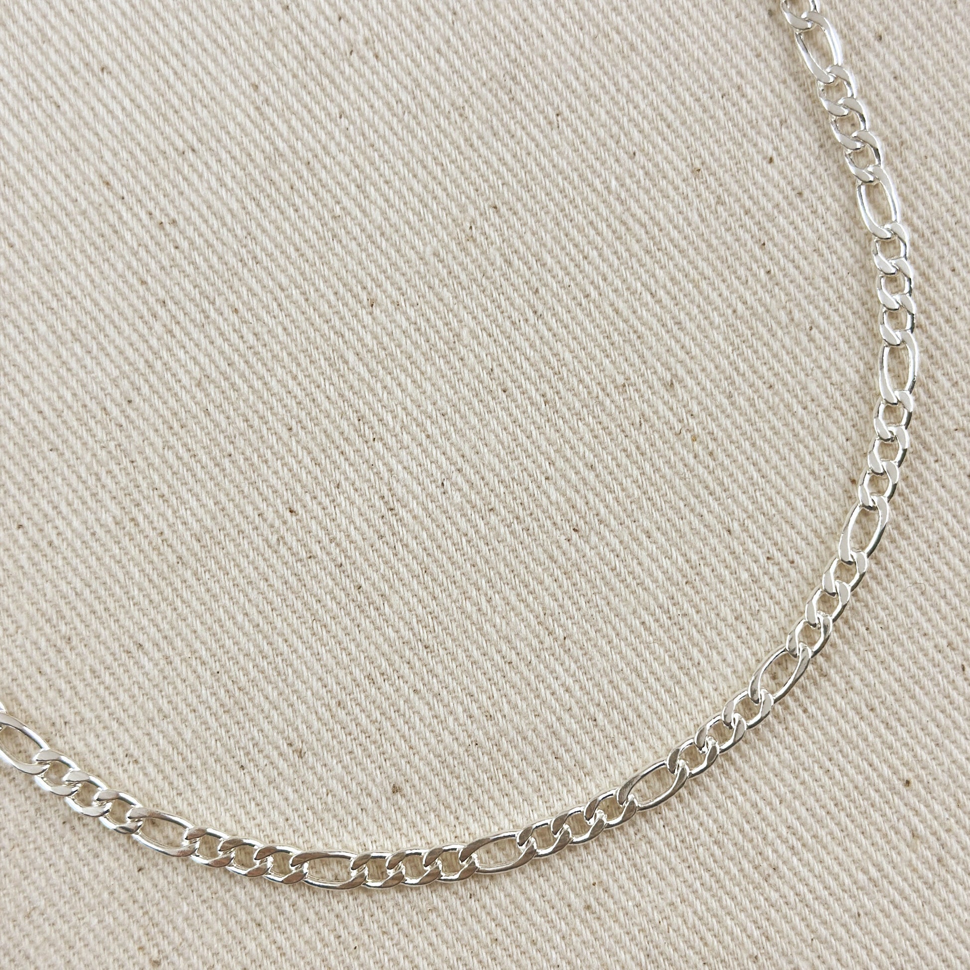 Silver chain necklace on a beige fabric background