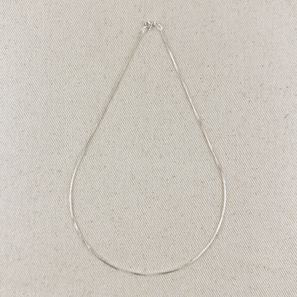 Silver necklace on a light gray textured background