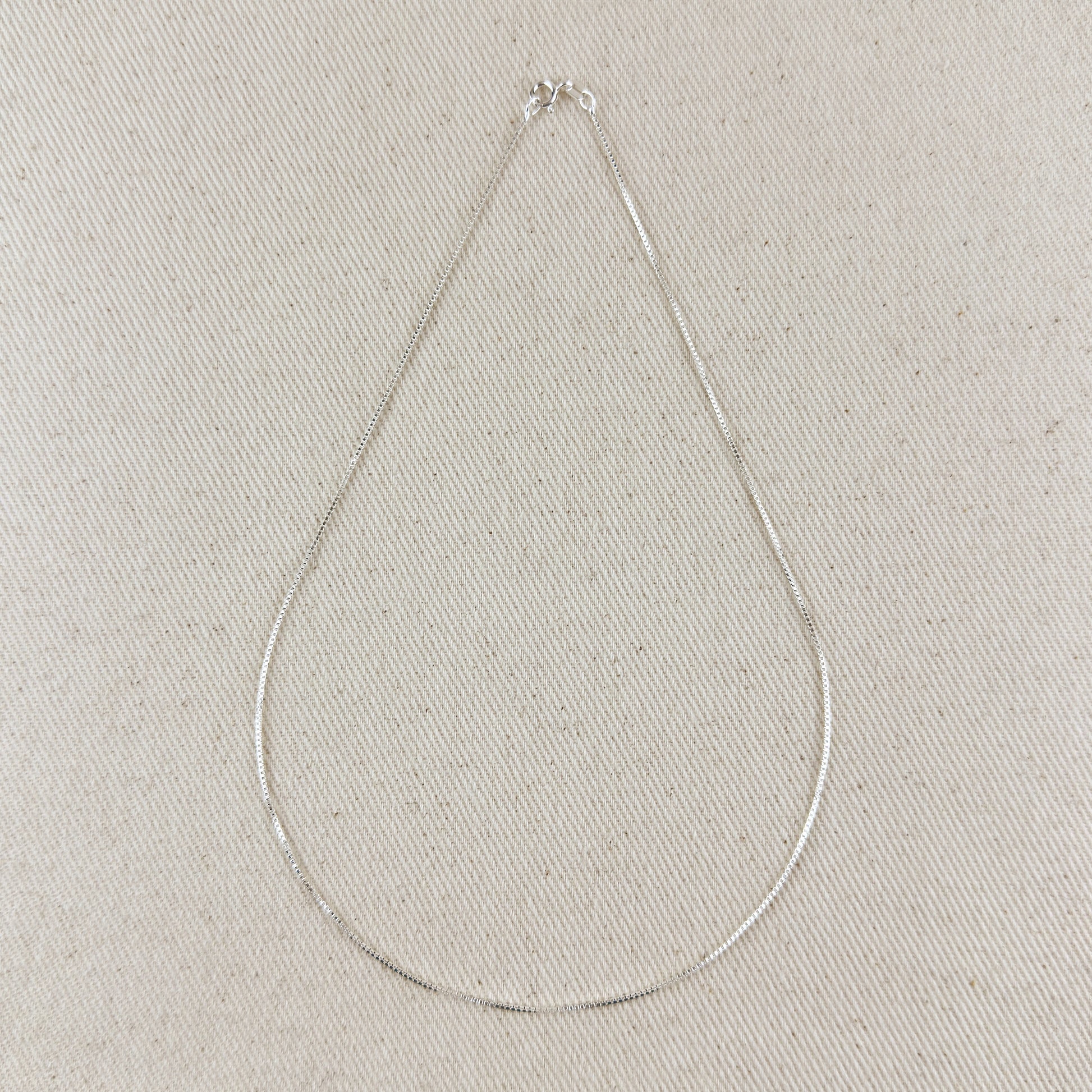 Silver necklace on a light gray textured background