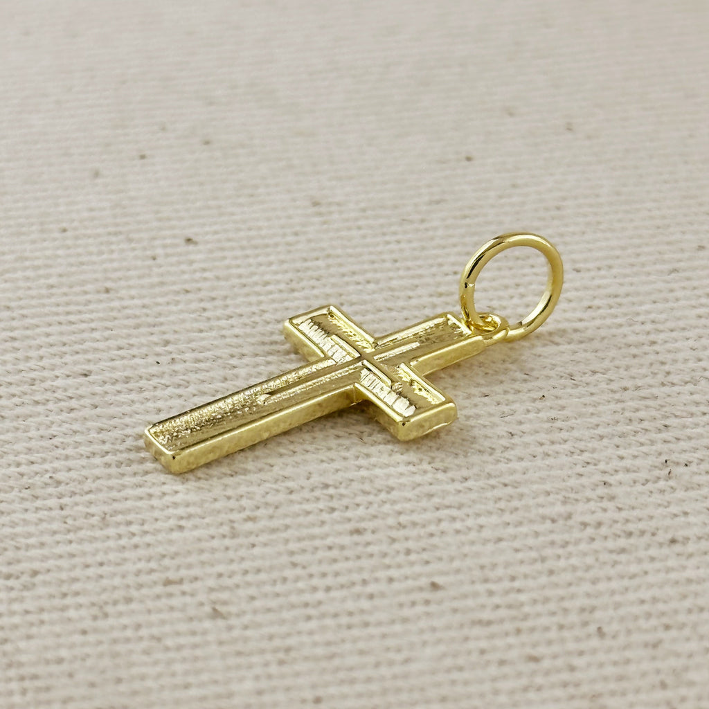 Gold cross pendant on a beige fabric background