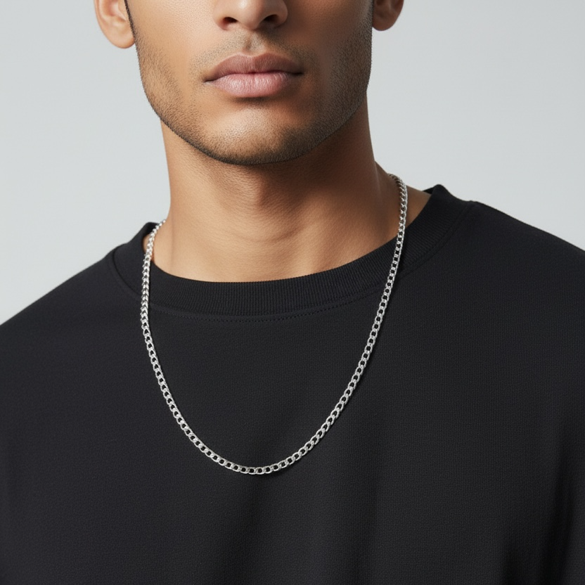 Man wearing a silver chain necklace against a plain background