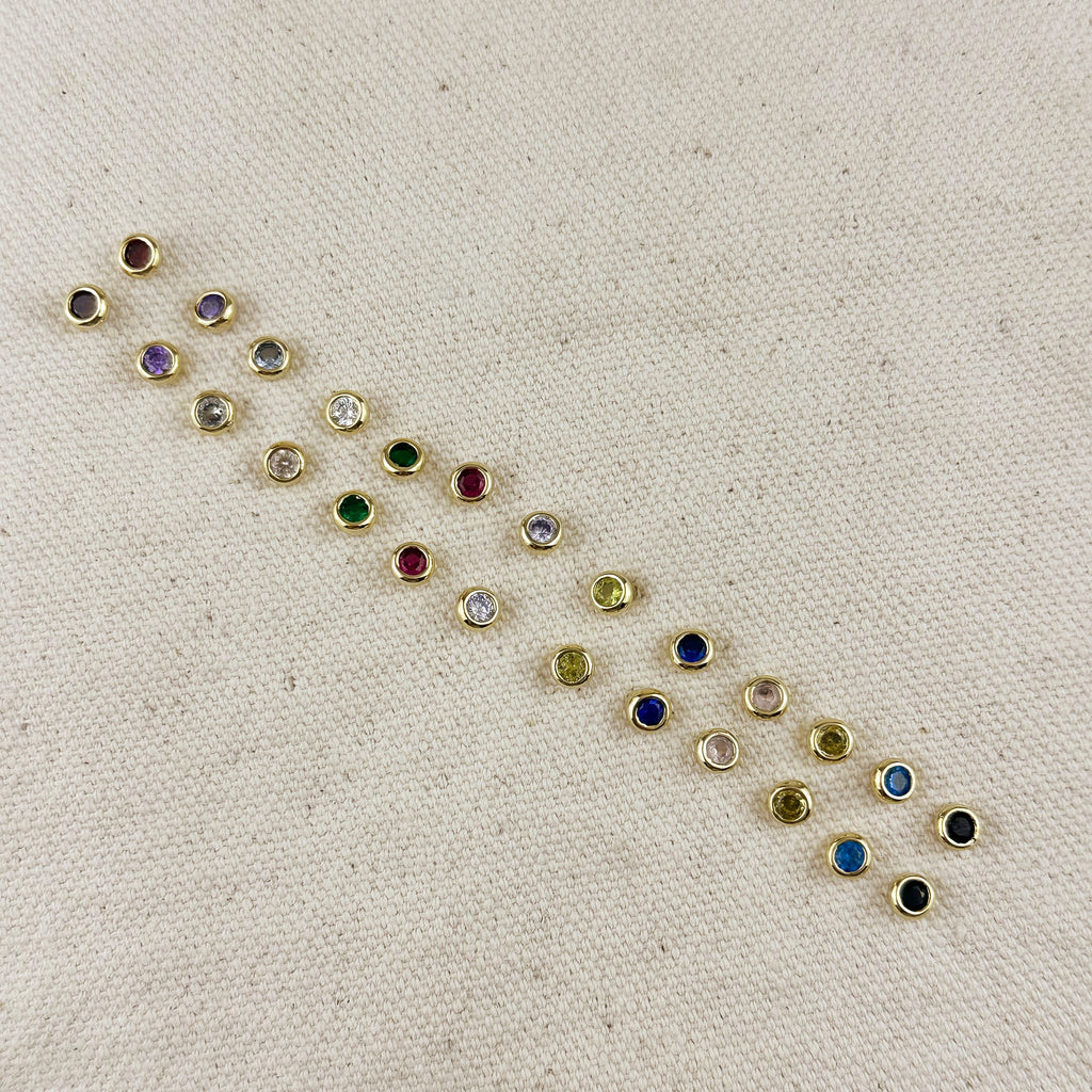 Small gemstone earrings on a beige fabric background