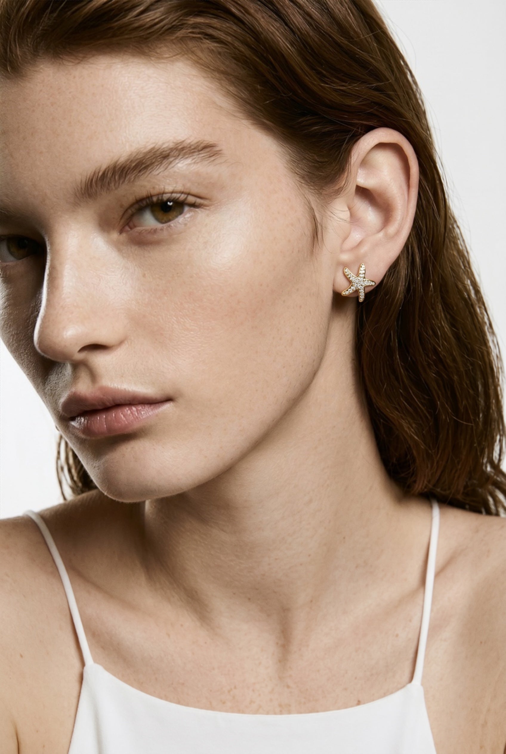 Close-up of a woman wearing a star-shaped earring with a neutral background