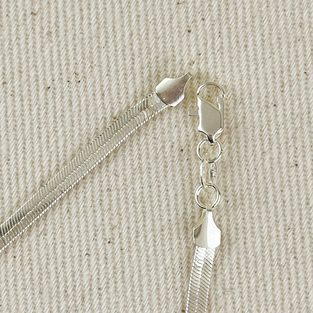 Close-up of a silver chain with clasp on a textured beige background