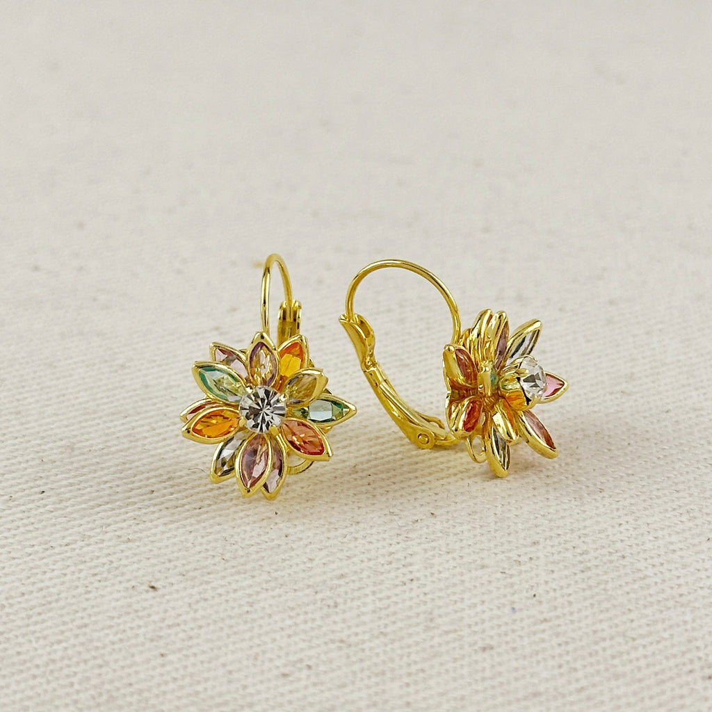 Gold floral earrings with multicolored stones on a beige background