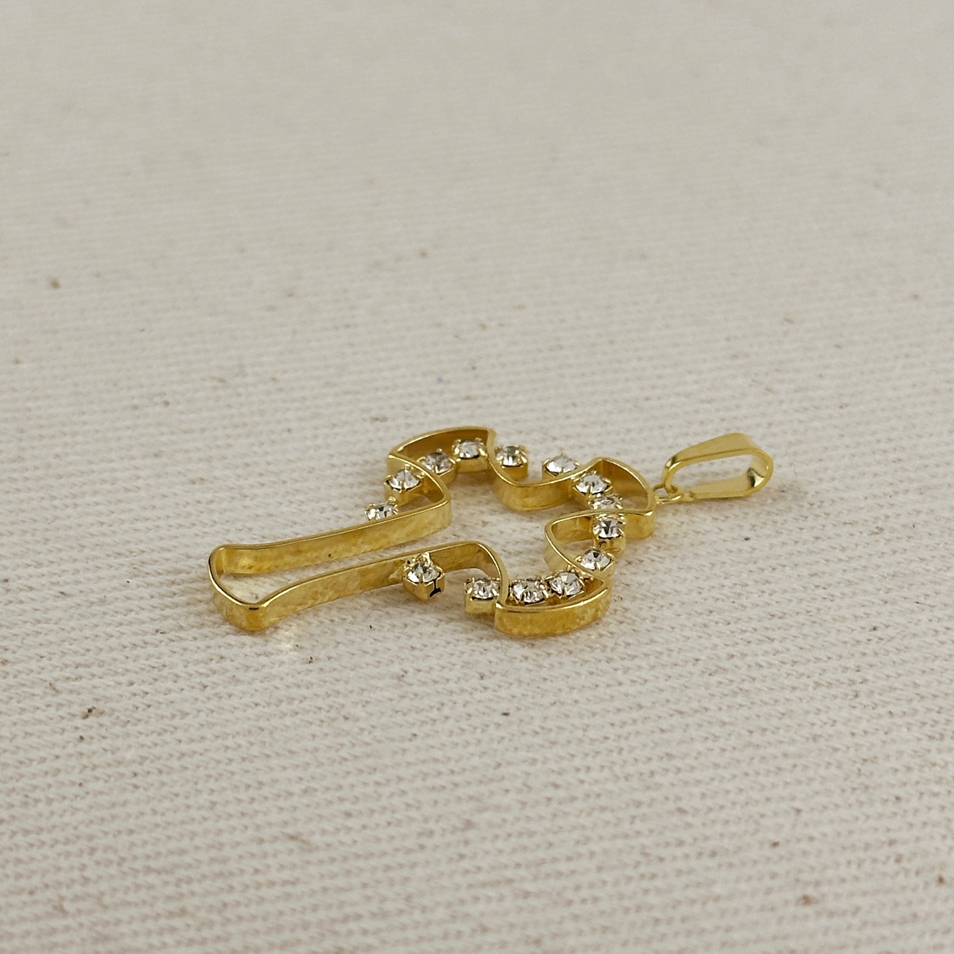 Gold pendant with embedded stones on a beige fabric background