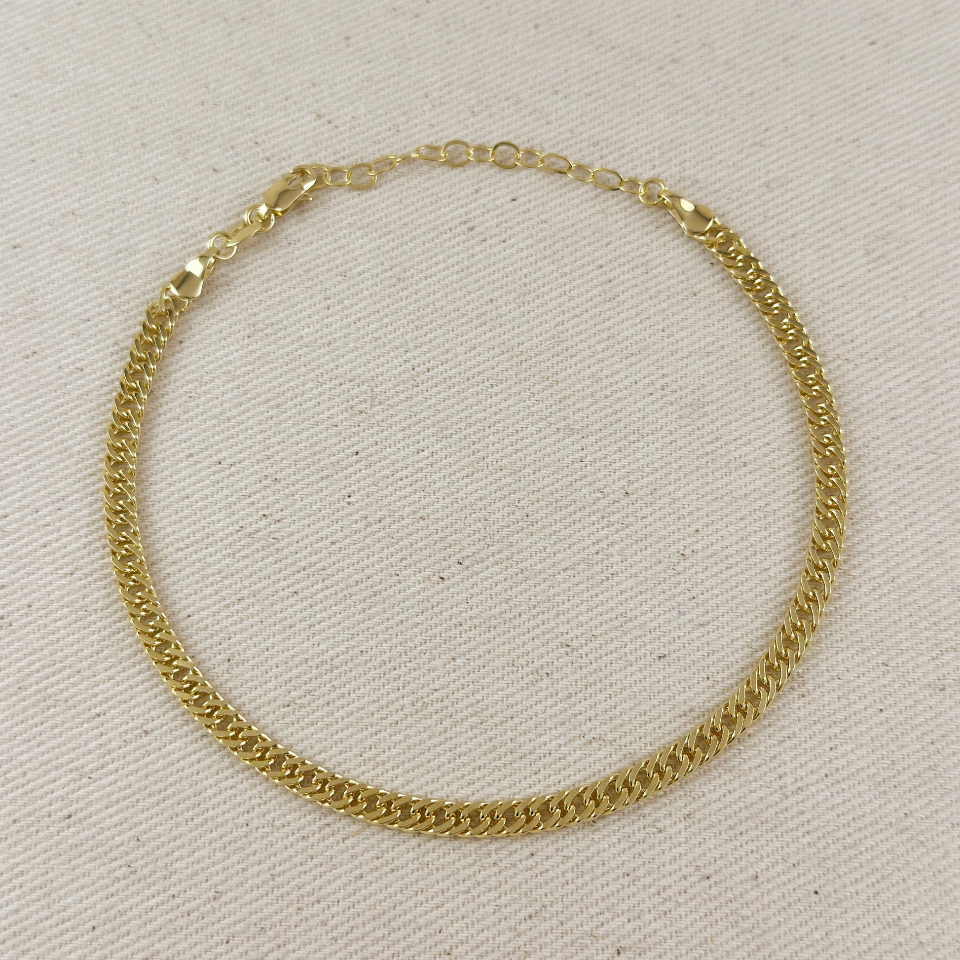 Gold chain necklace on a light beige fabric background