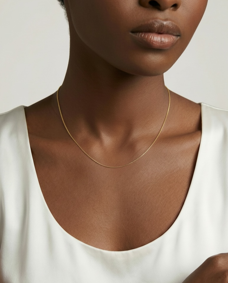 Woman wearing a delicate gold necklace against a plain background