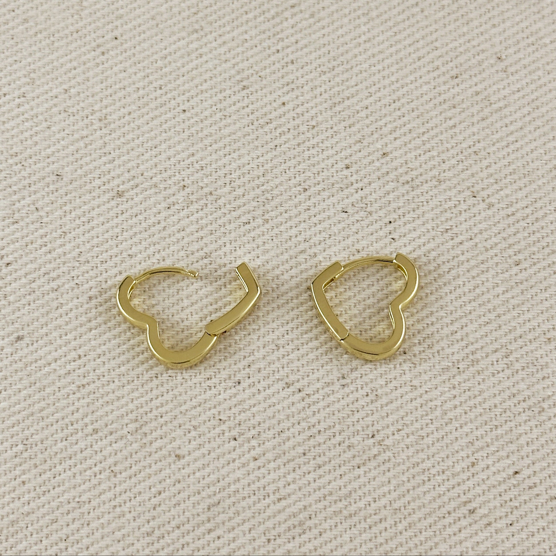 Gold hoop earrings on a beige fabric background