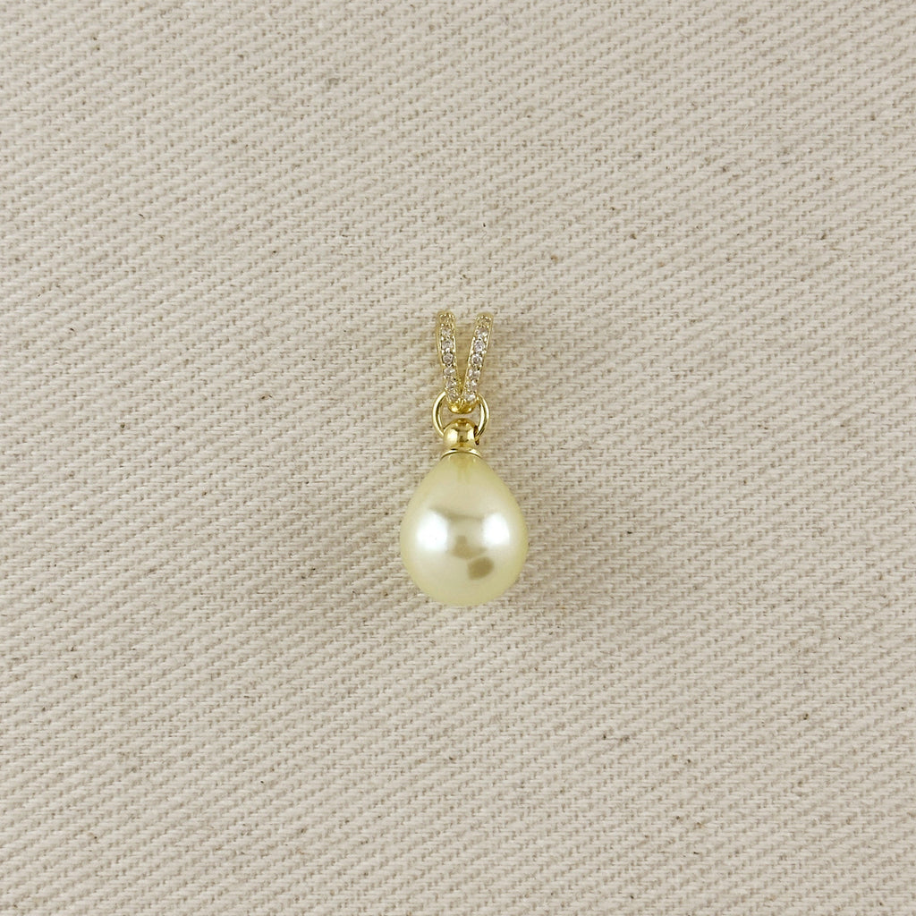 Pearl pendant on a gold chain against a beige fabric background