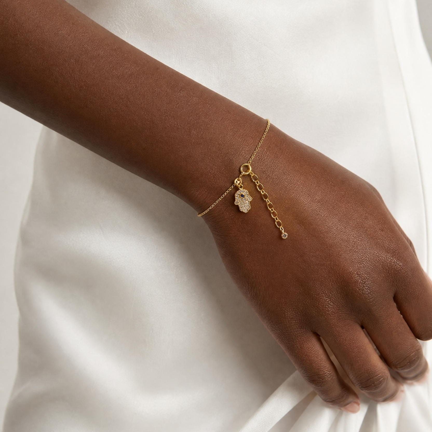 Gold bracelet on a wrist against a white fabric background
