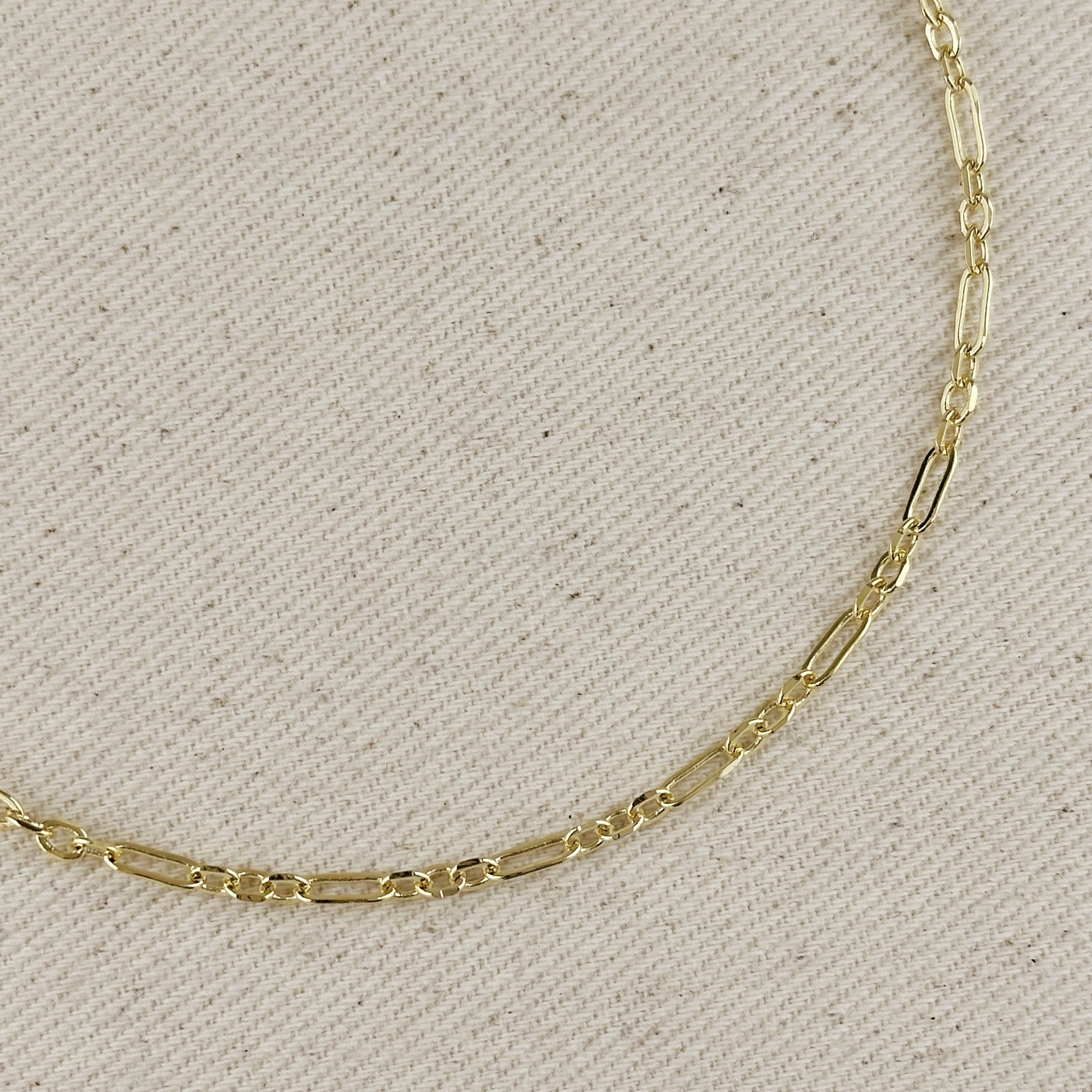 18K gold filled paperclip chain necklace with 3x1 alternated link pattern on textured background.