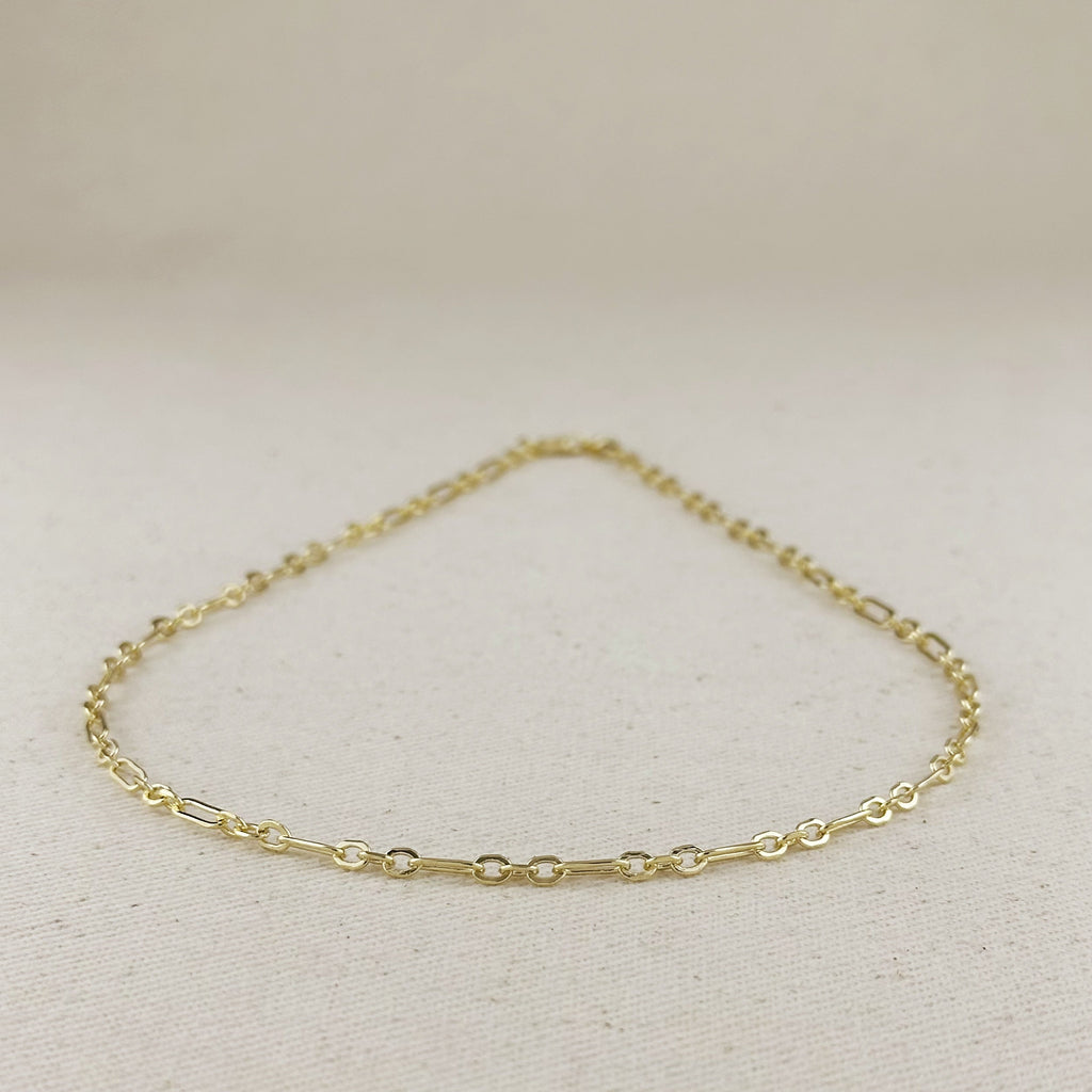 Gold chain bracelet on a light beige background