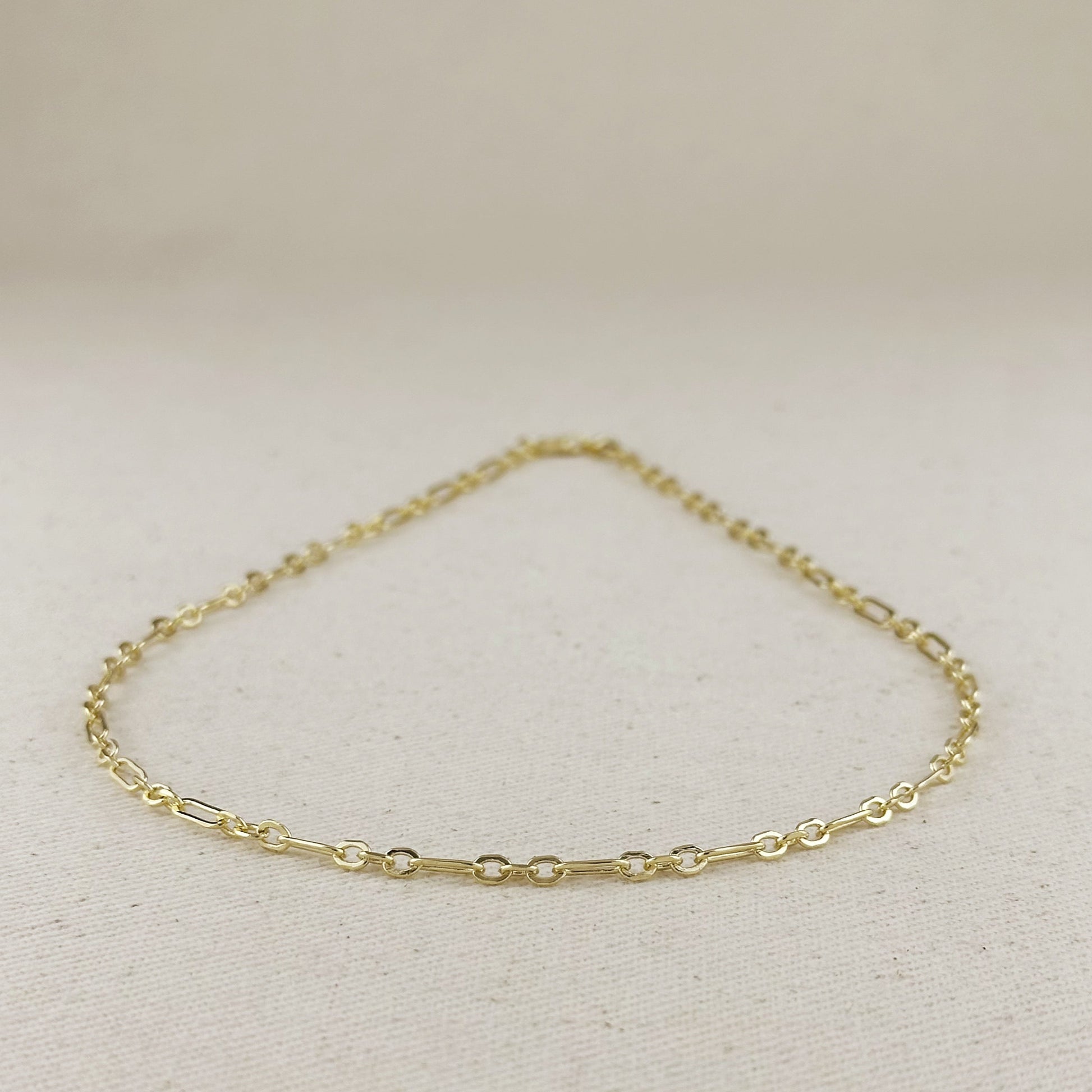 Gold chain bracelet on a light beige background