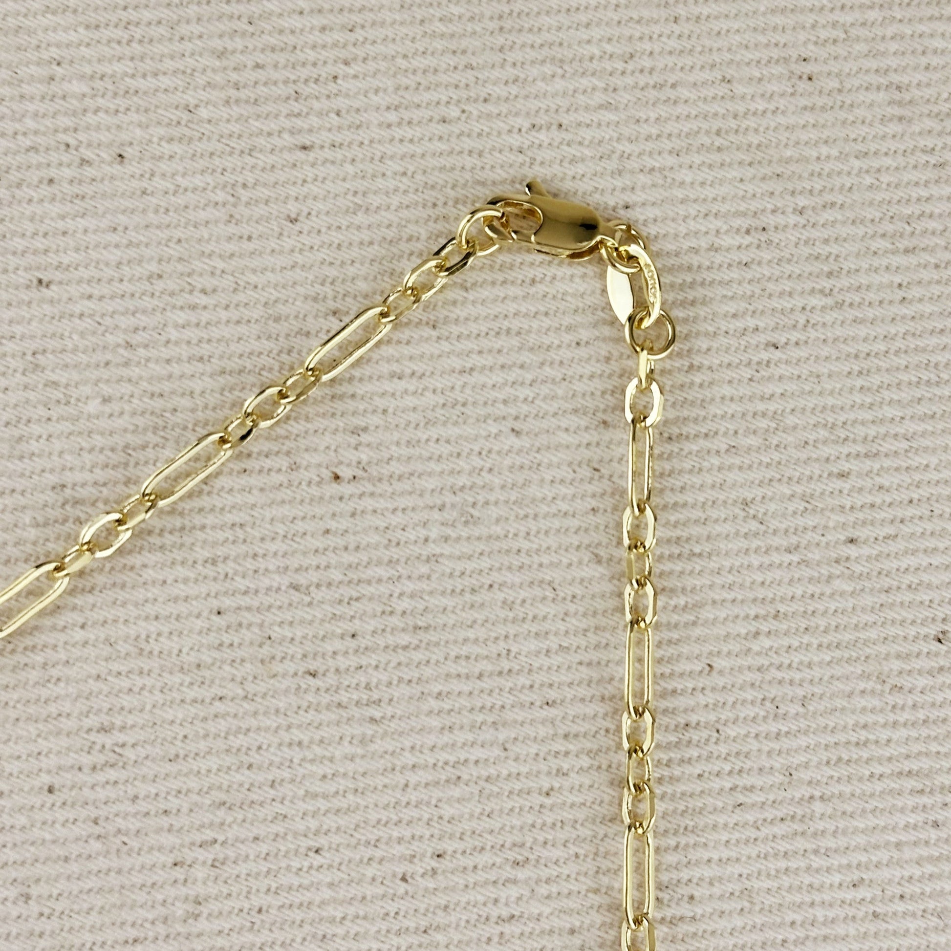 Gold chain clasp on a light gray fabric background