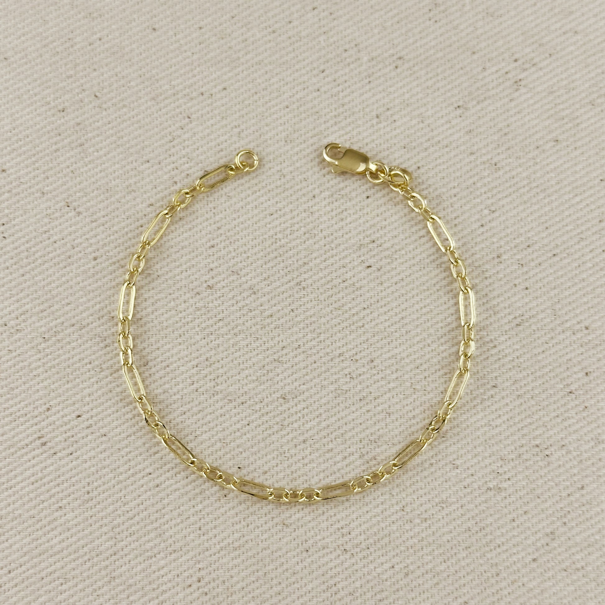 18K gold filled 3x1 alternated paperclip bracelet on neutral fabric background.