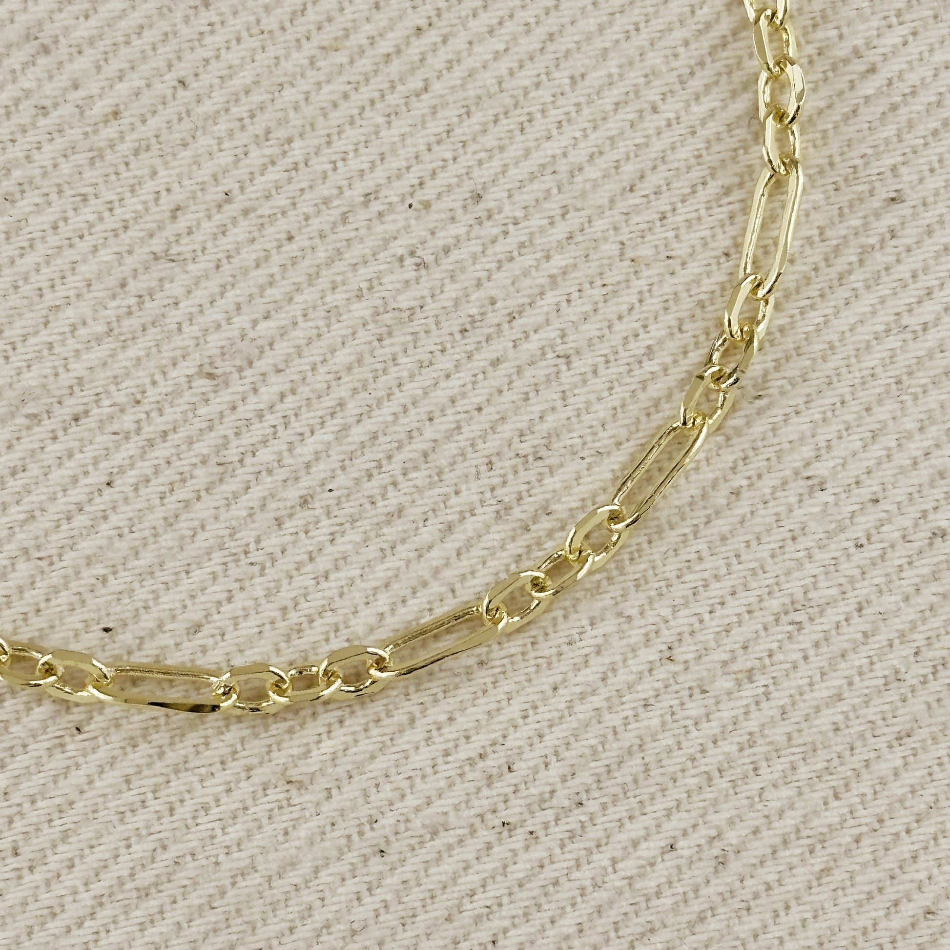 Close-up of an 18K gold filled paperclip bracelet showcasing a 3x1 alternated link pattern on a neutral background.