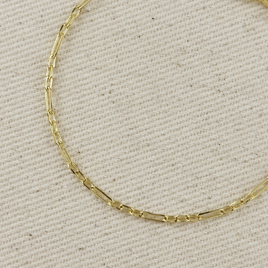 Close-up of an 18K gold filled paperclip bracelet with a 3x1 alternated link pattern on a neutral fabric background.