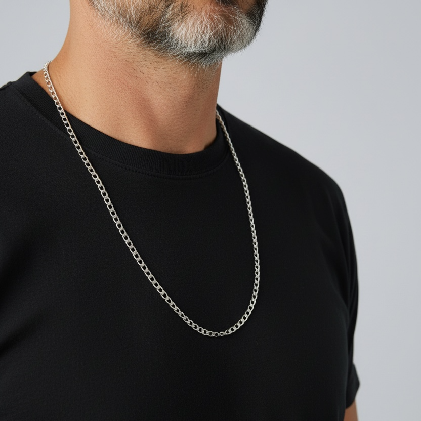 Person wearing a black t-shirt and silver chain necklace on a plain background