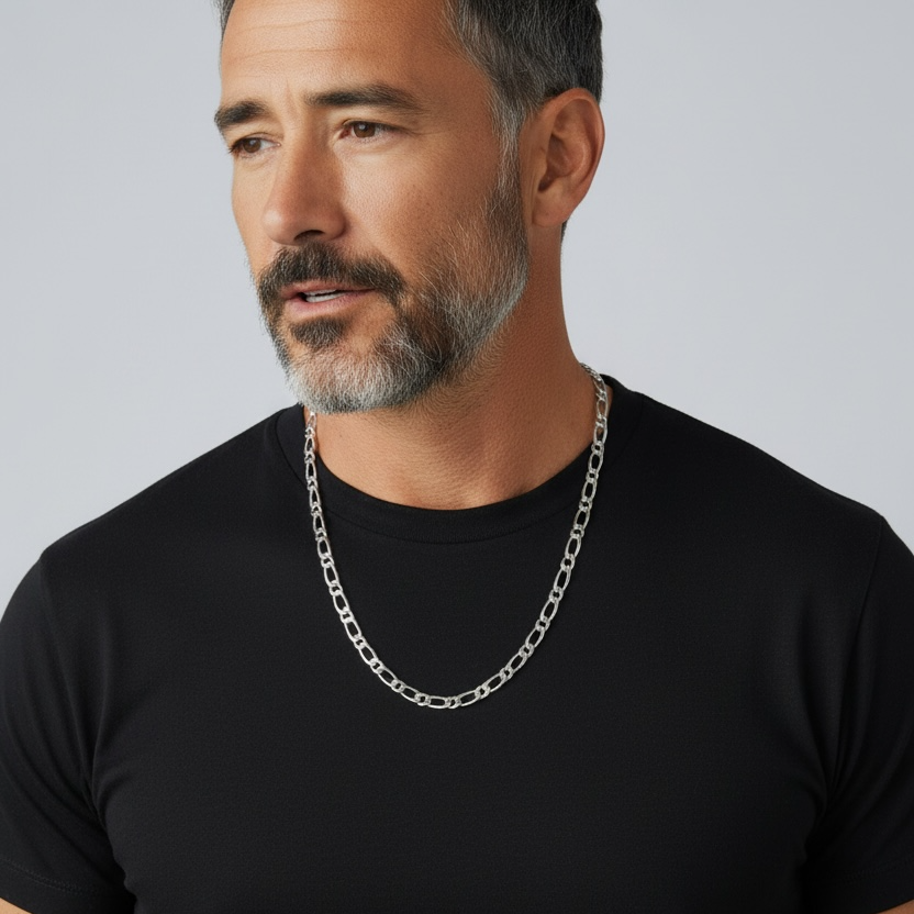 Man wearing a black t-shirt and silver chain necklace against a gray background
