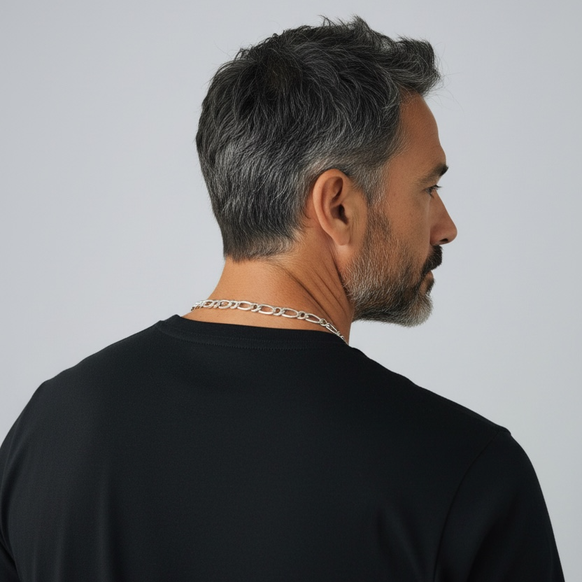 Man wearing a black t-shirt and chain necklace against a plain background