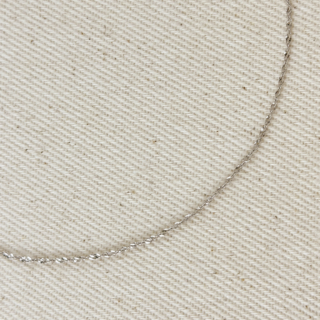Close-up of a silver chain on beige fabric
