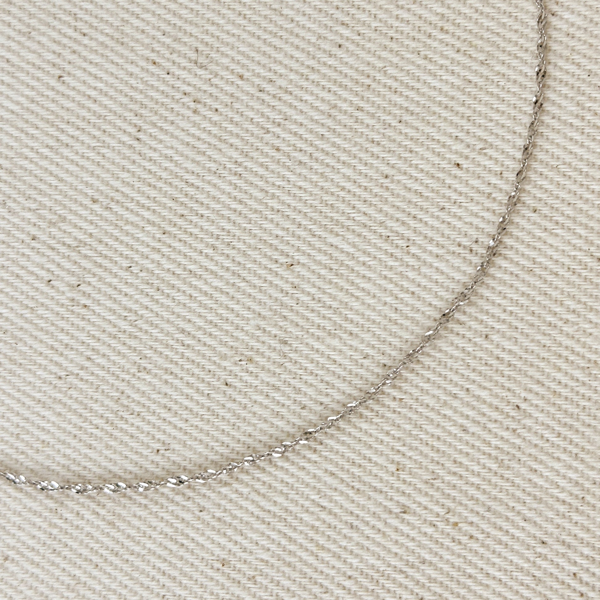 Close-up of a silver chain on beige fabric