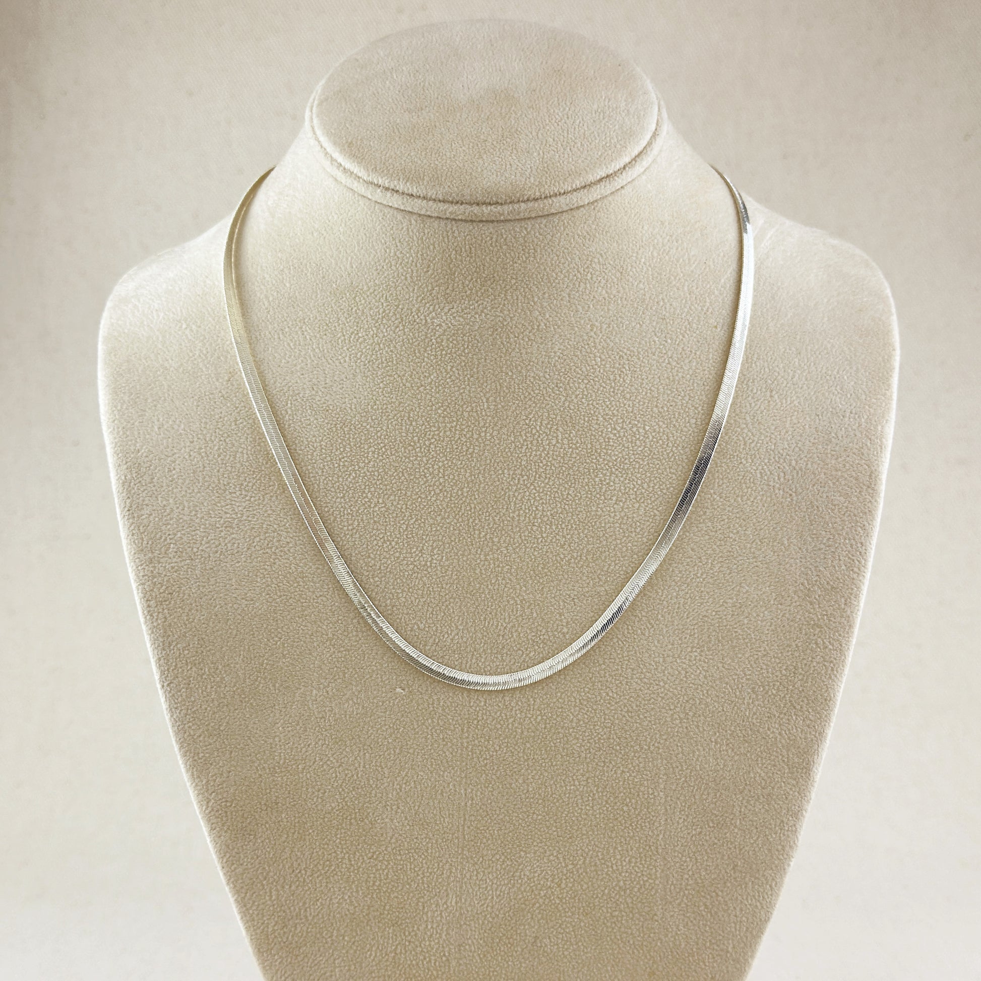 Silver necklace on a beige velvet mannequin bust
